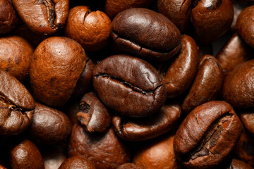 Naklejka premium A macro close-up of roasted coffee beans showcasing their rich brown color, detailed texture, and natural oils. The beans are tightly packed, emphasizing their unique shapes and surface patterns.