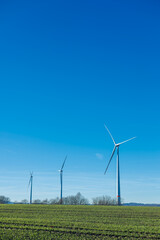 Wind energy generation. Electricity is generated by a wind turbine against a blue sky. Sustainable energy production in a windy green zone. Ecological energy generation