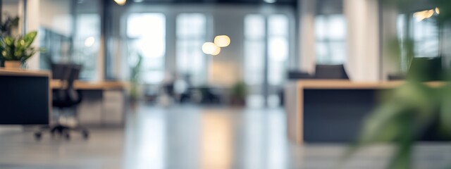 Blurred open space office interior showing desks and plants