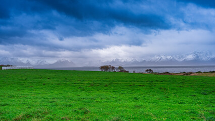 Obraz premium Bright green Field With blue clouds and sky With Mountains in The background
