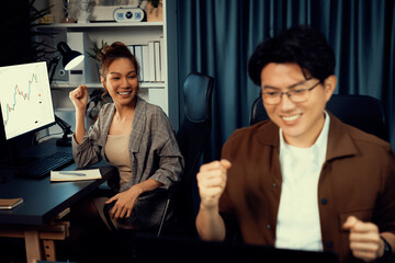 Successful wealthy of smiling business trader with partner in casual suit earning high profit raising fist up in exchange stock market investment in technology at modern office at night. Infobahn.