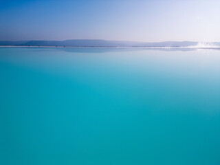 A mesmerizing turquoise lake with a soft gradient sky and a calm horizon. The serene waters and minimalistic composition highlight the harmony and tranquility of nature's beauty