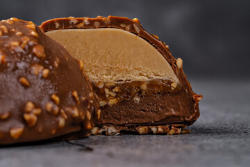 Close-up of a Chocolate Ice Cream Dessert with Layers of Caramel and Nuts on a Dark Stone Background