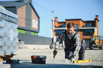 The master in gloves lays paving stones in layers. Garden brick pathway paving by professional...