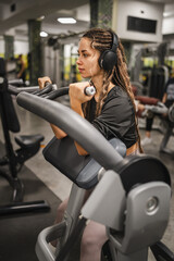 Fototapeta premium young woman in sportswear do exercise shoulder and hands at gym machine
