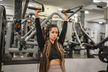 young woman in sportswear do shoulder exercise at the gym machine