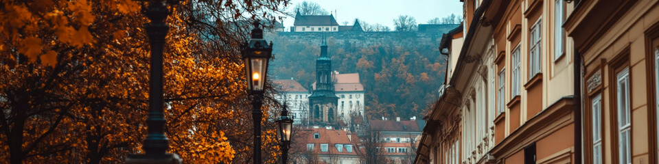 Obraz premium Street lined with lanterns and buildings, with a distant view of a castle-like structure on a hill. Concept of urban architecture and autumn scenery. For travel photography.