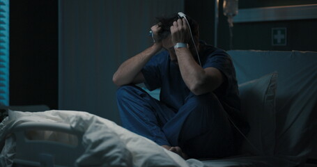 Fototapeta premium Man holds head, rocks on bed, looks unwell.