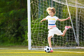 Child playing football. Kids play soccer.