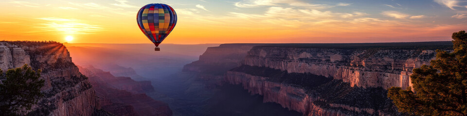 Obraz premium Hot air balloon floats over a vast canyon at sunset, casting a colorful silhouette against the sky. Concept of adventure and exploration. For travel postcard.
