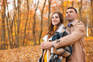 Fototapeta premium Happy couple spending time together in autumn park, space for text