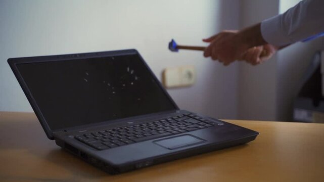 Anger management issues. Male rage. Tech fail. Tecnhnical problems. Man smashing laptop with hammer