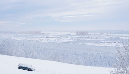 Obraz premium 폭설로 인해 도시가 눈에 파묻힌 모습, 건물들과 차량들이 눈 아래에 묻혀 있다