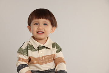 Portrait of happy little boy on light grey background. Space for text