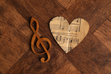 Paper heart and clef note on wooden table, top view