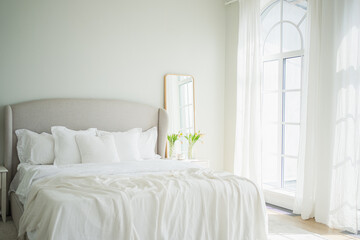 Stylish loft bedroom interior. Spacious design apartment with light walls large windows big bed. Clean modern decoration with elegant furniture in minimalist Scandinavian style