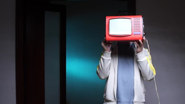 a man has a TV instead of a head. Man holding portable television in front of face