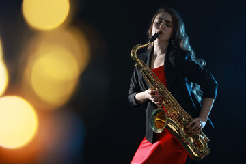 Professional musician playing saxophone on black background with blurred lights. Bokeh effect