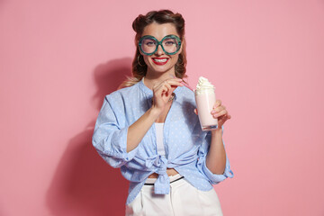 Happy pin-up woman with milk shake on pink background