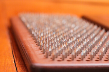 The Sadhu board is a traditional wooden tool used for meditation and mindfulness practices. The Sadhu board was made of warm pine wood with silver nails, forming a symmetrical grid, close-up