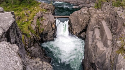 Majestic waterfall cascading through rocky gorge under wooden bridge