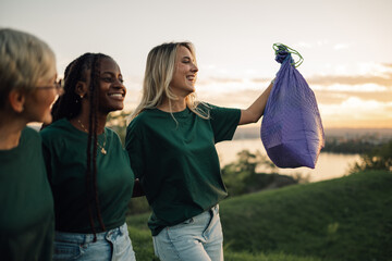 Three volunteers walking and holding trash bag in nature