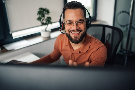 Smiling male call center agent working on computer in office
