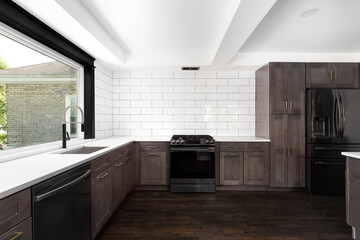 A kitchen with modern hardwood cabinets, white subway tile backsplash, white marble countertop, and white beam ceiling.