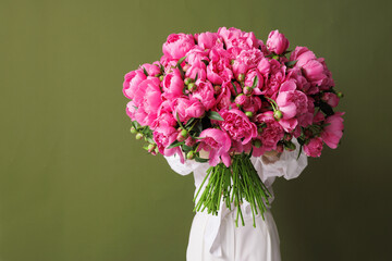 Young woman covering her face with bouquet of Young woman covering her face with bouquet of peonies on green background on white background