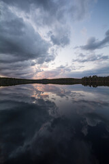 Clouds and forests reflected on the surface of a calm lake in Finland