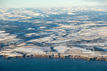 Aerial of snow covered Scottish North Sea coastline with white fields