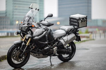 A large black touring motorcycle is covered in snow. The end of the motorcycle season, winter. The inscriptions "Stupid snow, No, WTF" symbolize stubbornness and the desire to continue traveling