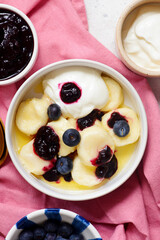 Lazy cottage cheese dumplings with blueberry sauce, sour cream and butter.top veiw