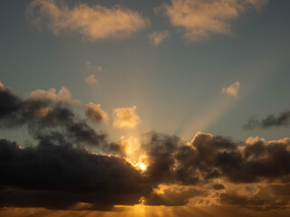 Dark dramatic sunset sky with clouds and sun beams and flare. Nature background for design and sky replacement.