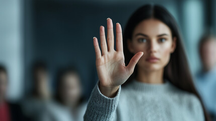 Professional woman holding her palm outward in a Stop gesture emphasizing inclusivity and boundary-setting in the workplace.