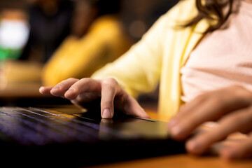 Young pupil engaged in a homework session at the school library, working on writing an essay on her laptop. PC tech to prepare for the literature class, vibrant academic environment. Close up.