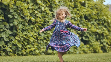 Naklejka premium Young girl spinning amid lush garden, flowing dress capturing joyful family moment