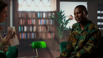 African american soldier in military uniform sits with an expert, viewing a Rorschach test...