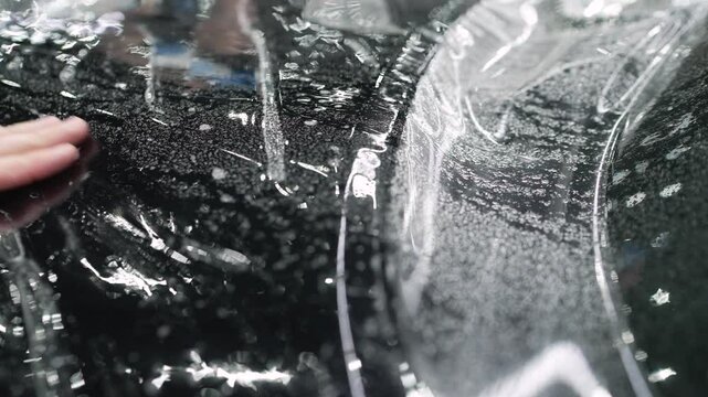 Professional applying protective film on a car hood