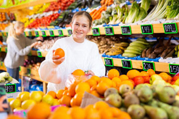 Portrait of teenage girl customer buying sweet oranges at grocery shop