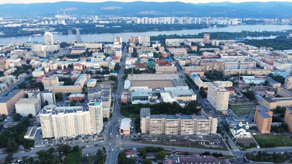 Aerial view of krasnoyarsk city center showcasing the yenisei river, central stadium, residential buildings, and urban infrastructure during the evening