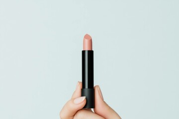 Obraz premium A close up of a hand holding a nude lipstick against a soft pastel background, showcasing beauty and elegance with a minimalist style that highlights cosmetic products