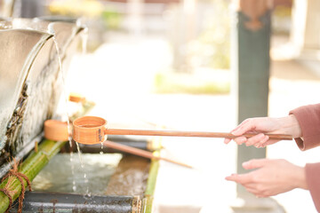 A shrine in Hakata, Fukuoka, Japan. A Japanese woman with a long hair in her thirties cleans her hands using a ladle.