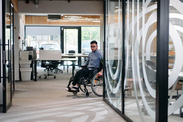 In a large modern corporation, a determined businessman in a wheelchair navigates through a...