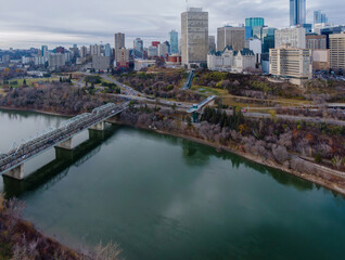 Obraz premium High-angle view of the city of Edmonton, Alberta, Canada, with the North Saskatchewan River and a bridge. Urban landscape, featuring skyscrapers, parks, and a pedestrian bridge. Alberta, Canada
