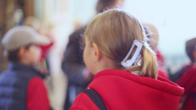 Group of kids children on excursion in a museum gallery, school pupils and students tour with guide, a docent with a tourists, young visitors wearing red, school field trip, art exhibition attendees