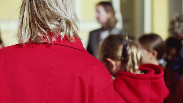 Group of school pupils and students on outdoor excursion tour in the city streets with guide, a docent with a tourist young visitors wearing red, school field trip, urban tour in the summer sunny day