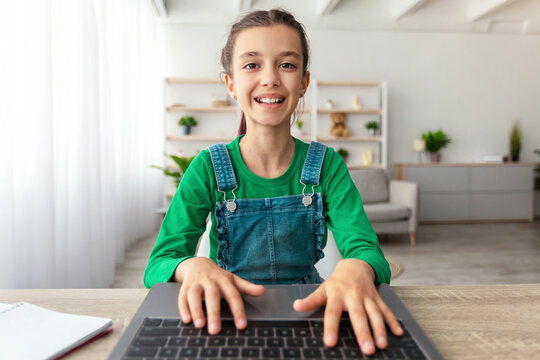 Doing Homework. Portrait of smiling student using laptop, studying online at home, happy girl typing on keyboard looking at pc screen, chatting with friends or making school research, web camera pov