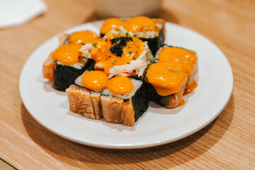 salmon kani lava roll, sushi roll features tempura flakes and is topped with salmon, Japanese omelette, crab stick, mayonnaise, spicy sauce, and spicy tempura flakes