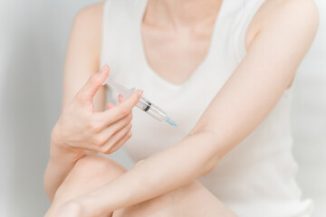 注射器で覚醒剤・薬物・違法ドラッグを腕に打つ女性

